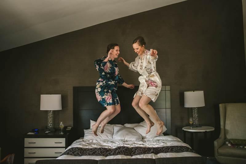 Industrial chic April wedding bridal party jumping on a bed in Baltimore City's Radisson Hotel by Britney Clause Photography