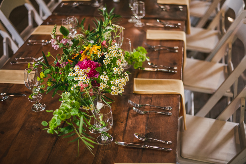 Gorgeous summer wedding reception details using farmhouse tables and Sungold Flower Co florals at Rocklands Farm Winery in Poolesville, Maryland by Britney Clause Photography a husband and wife wedding photographer team in Maryland