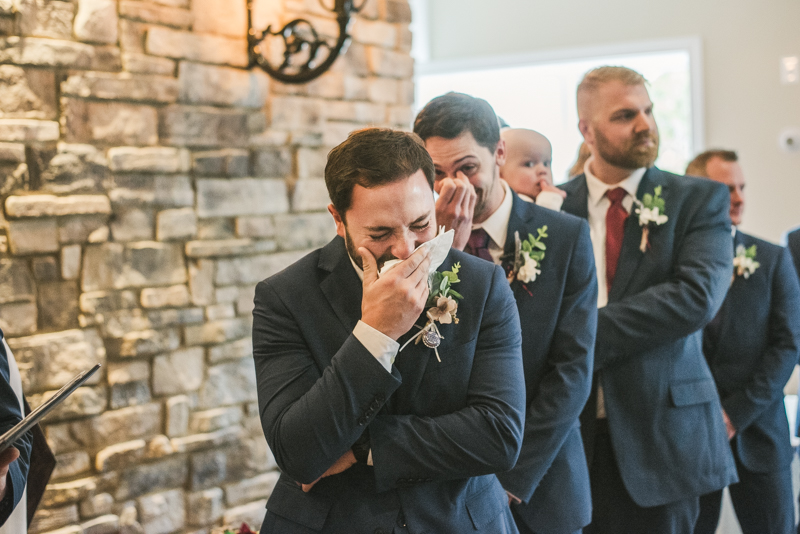 An emotional groom waiting for his bride at the end of the aisle at Kurtz's Beach in Pasadena, Maryland. Photo by Britney Clause Photography