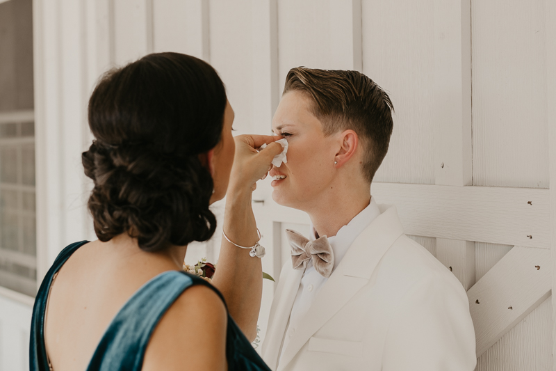 Two brides sharing a first touch at Kylan Barn in Delmar, Maryland by Britney Clause Photography