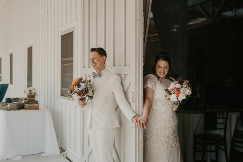 Two brides sharing a first touch at Kylan Barn in Delmar, Maryland by Britney Clause Photography