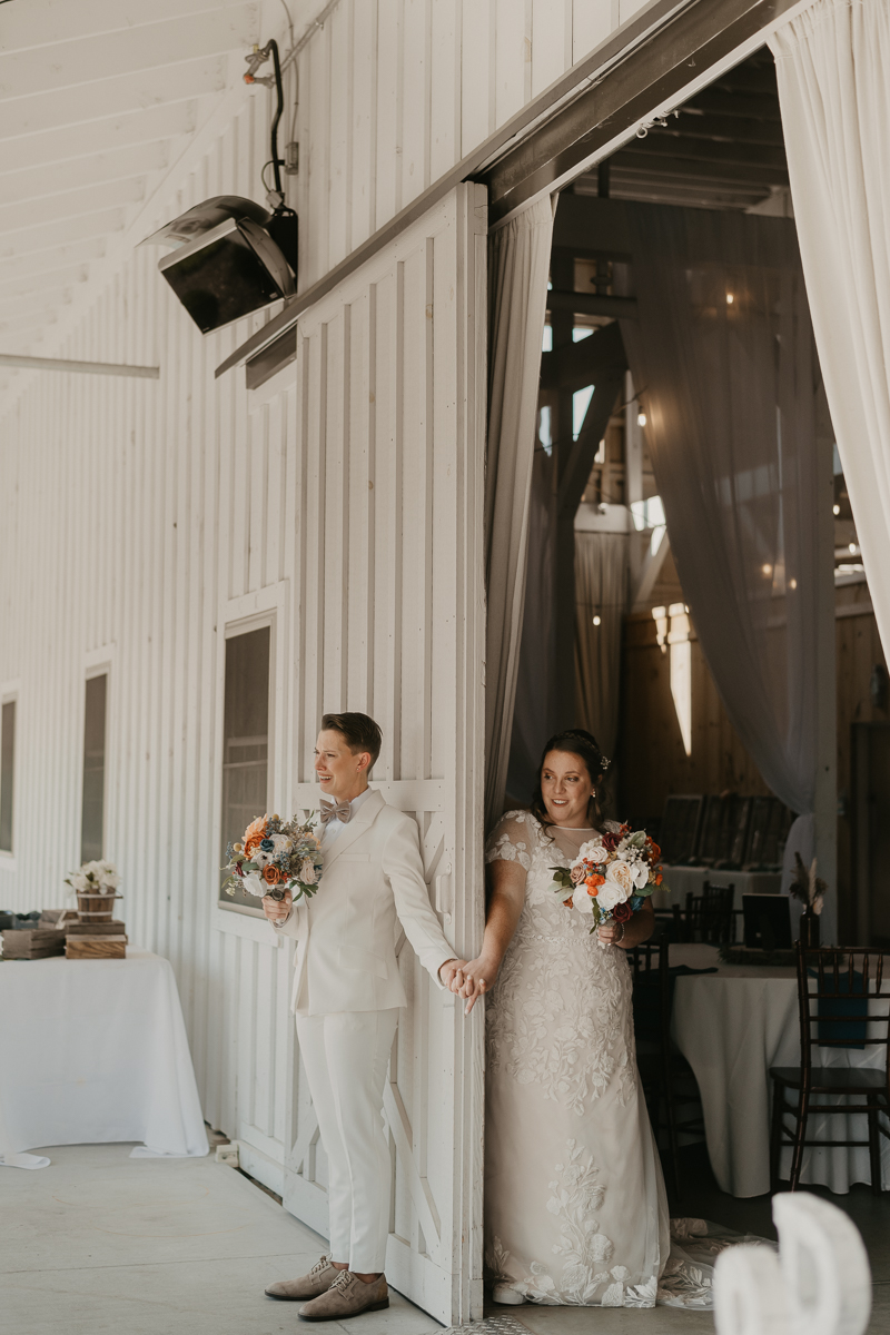 Two brides sharing a first touch at Kylan Barn in Delmar, Maryland by Britney Clause Photography