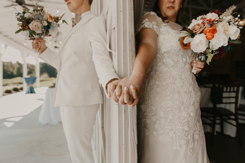Two brides sharing a first touch at Kylan Barn in Delmar, Maryland by Britney Clause Photography